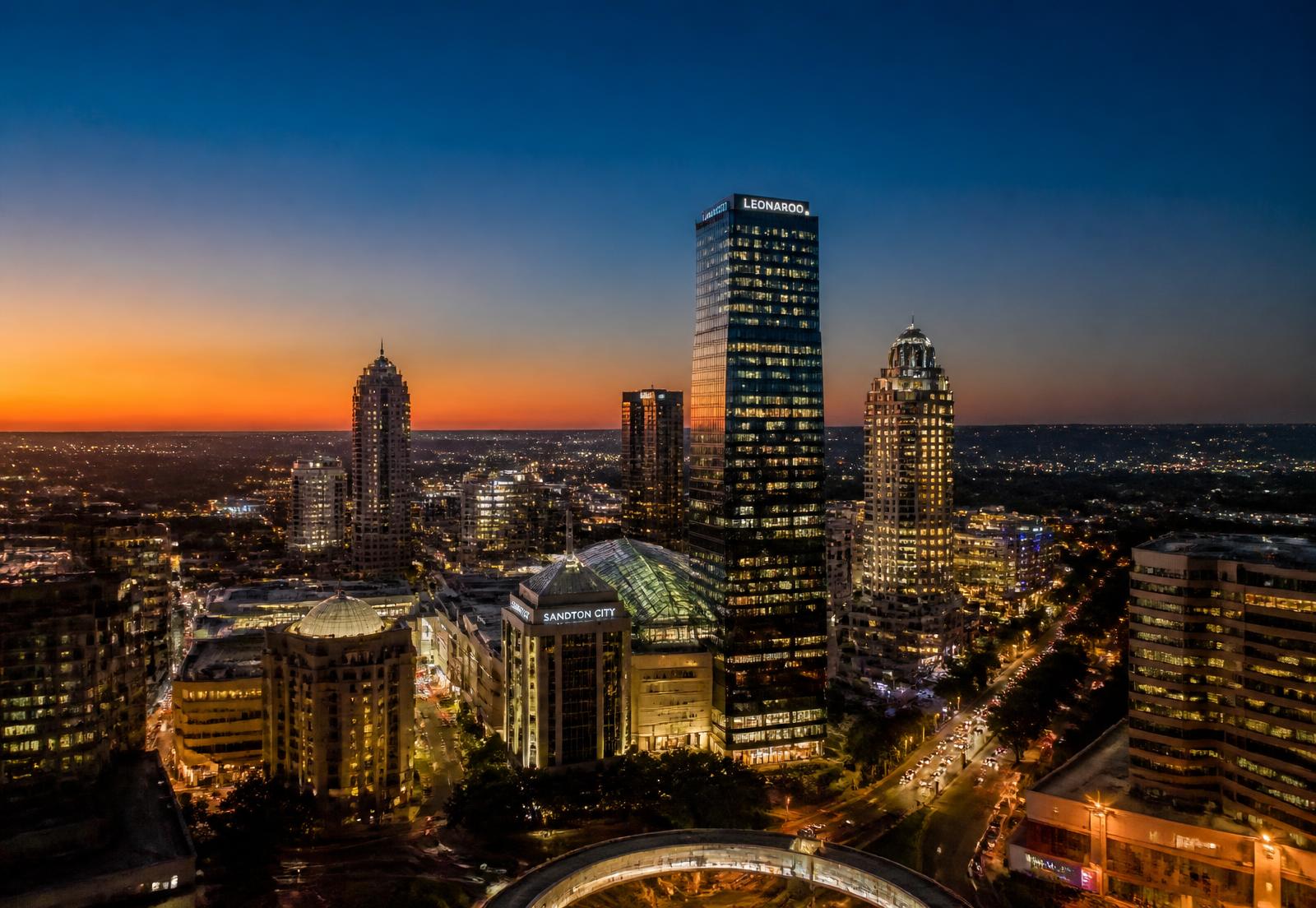 Aerial view of the Johannesburg Sandton skyline at dusk with warm city lights